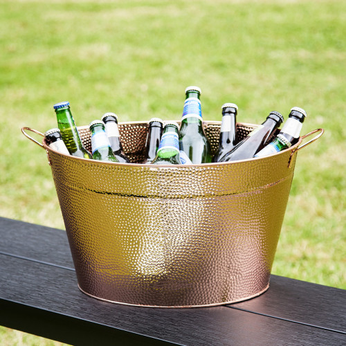 Copper and steel shiny drinks pail filled with beer and with grass in the background.